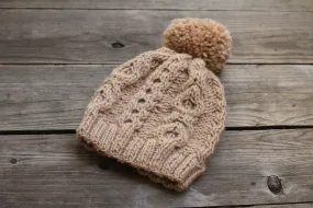 Knit beanie hat in beige color with cables and pom pom