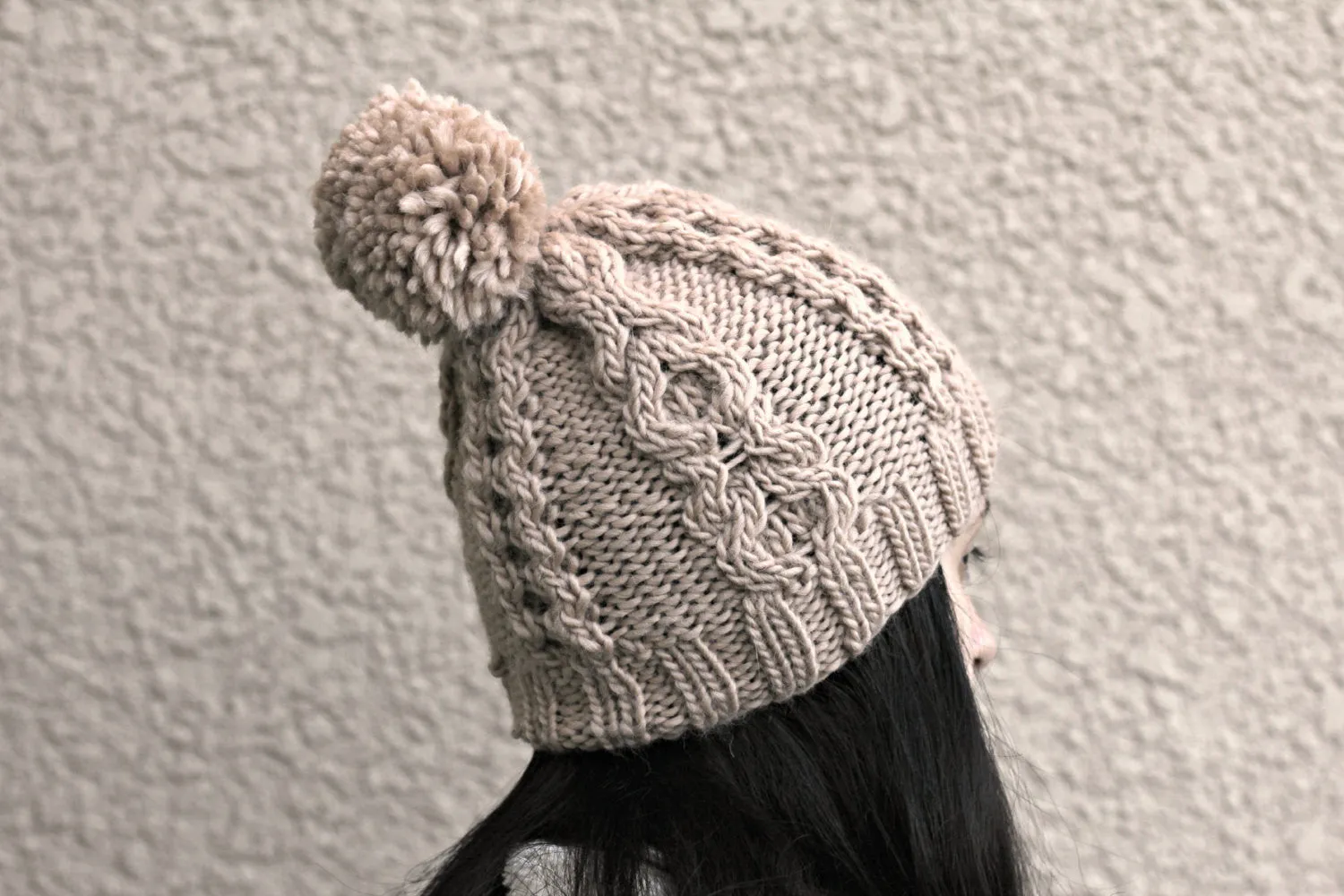 Knit beanie hat in beige color with cables and pom pom