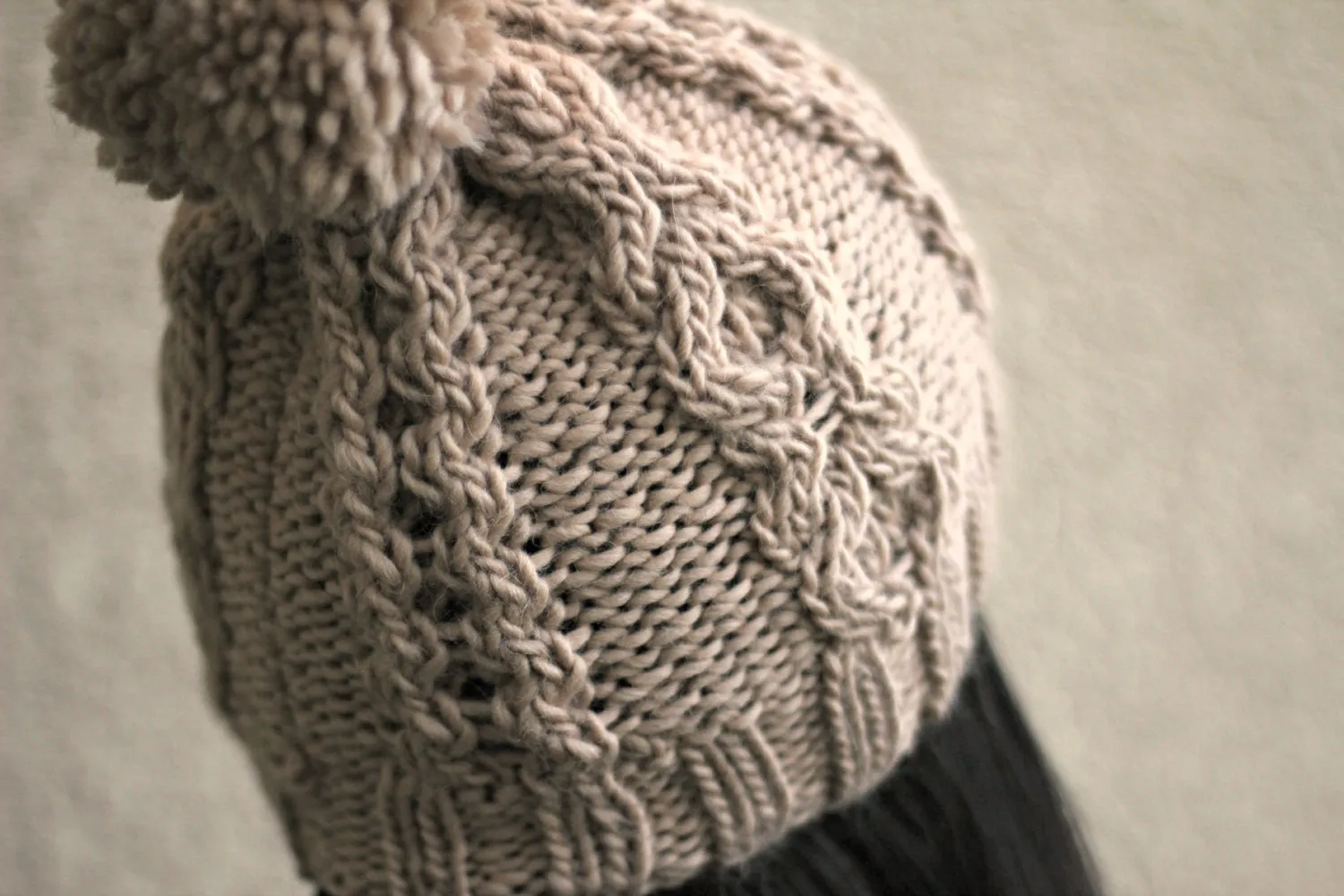 Knit beanie hat in beige color with cables and pom pom
